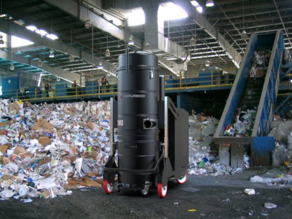 Depureco heavy-duty industrial vacuum operating in recycling facility beside conveyor and waste piles
